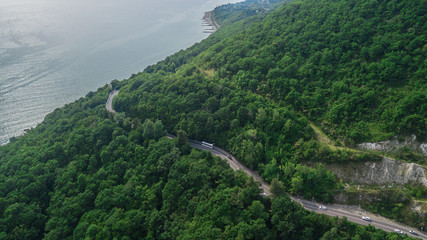 Fototapeta na wymiar Drones Eye View - winding road from the high mountain pass in Sochi, Russia. Great road trip trough the dense woods.