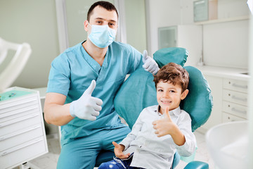 Happy dentist and child raised their thumb
