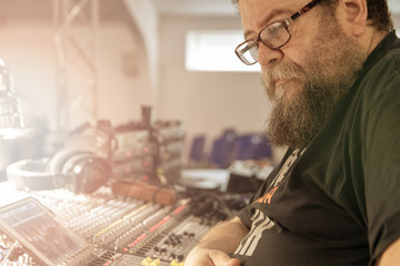 Sound engineer behind the sound mixing console controls the sound. Digital and analog sound mixer. ...