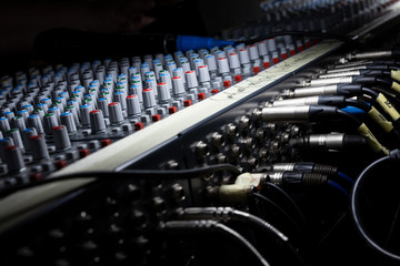 Sound engineer behind the sound mixing console controls the sound. Digital and analog sound mixer....