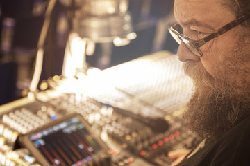 Sound engineer behind the sound mixing console controls the sound. Digital and analog sound mixer. ...