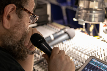 Sound engineer behind the sound mixing console controls the sound. Digital and analog sound mixer. ...
