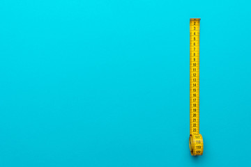 Top view of yellow soft measuring tape. Minimalist flat lay image of tape measure with metric scale...