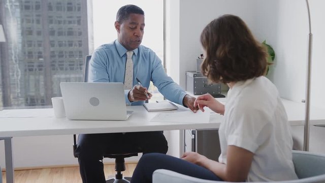 Woman Meeting With Male Financial Advisor In Office And Signing Contract
