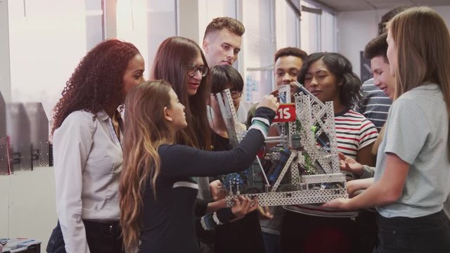 College Students With Female Teacher Holding Machine In Science Or Robotics Class