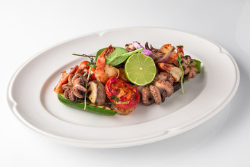 Luxurious seafood salad with shrimp, octopus, squid, fish, lime, cherry tomatoes, grilled vegetables and greens Banquet festive dishes. Fine dining restaurant menu. White background.