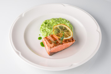 Grilled fish fillet salmon. Selected pieces of red fish with champagne and spinach risotto. Seafood. Banquet festive dishes. Fine dining restaurant menu. White background.