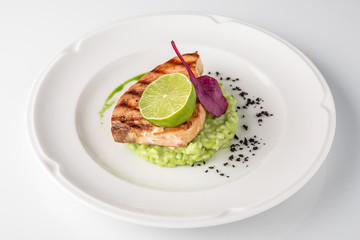 Grilled fish fillet salmon. Selected pieces of red fish with champagne and spinach risotto. Seafood. Banquet festive dishes. Fine dining restaurant menu. White background.