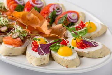 Bruschetta with salmon, avocado, capers, cucumber, radish, sweet pepper and cherry tomatoes. Banquet festive dishes. Fine dining restaurant menu. White background.