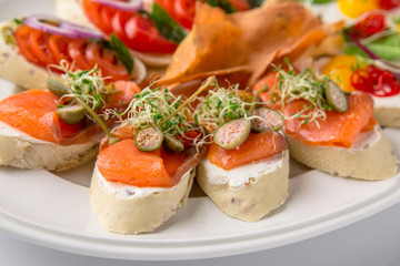 Bruschetta with salmon, avocado, capers, cucumber, radish, sweet pepper and cherry tomatoes. Banquet festive dishes. Fine dining restaurant menu. White background.