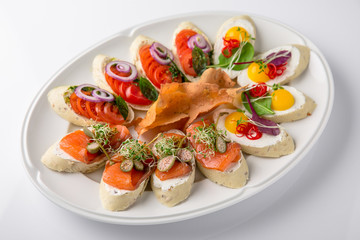 Bruschetta with salmon, avocado, capers, cucumber, radish, sweet pepper and cherry tomatoes. Banquet festive dishes. Fine dining restaurant menu. White background.