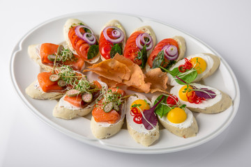 Bruschetta with salmon, avocado, capers, cucumber, radish, sweet pepper and cherry tomatoes. Banquet festive dishes. Fine dining restaurant menu. White background.