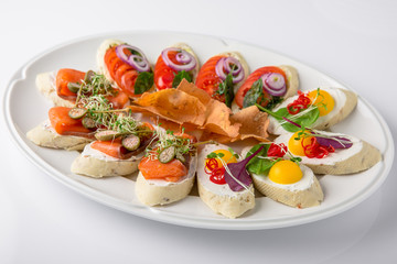 Bruschetta with salmon, avocado, capers, cucumber, radish, sweet pepper and cherry tomatoes. Banquet festive dishes. Fine dining restaurant menu. White background.
