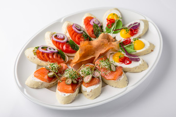 Bruschetta with salmon, avocado, capers, cucumber, radish, sweet pepper and cherry tomatoes. Banquet festive dishes. Fine dining restaurant menu. White background.