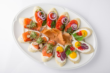 Bruschetta with salmon, avocado, capers, cucumber, radish, sweet pepper and cherry tomatoes. Banquet festive dishes. Fine dining restaurant menu. White background.