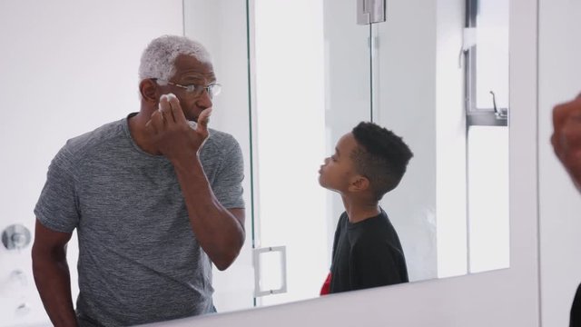 Grandfather Wearing Pajamas In Bathroom Shaving Whilst Grandson Watches
