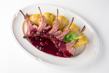 Rack of lamb in cherry sauce with pancakes stuffed with vegetables and cheese. Tender meat on the ribs. anquet festive dishes. Fine dining restaurant menu. White background. 