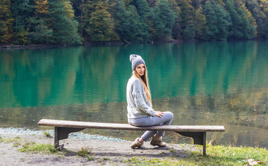 Girl in a hat and a gray tracksuit on the background of lake Ritsa in Abkhazia in autumn