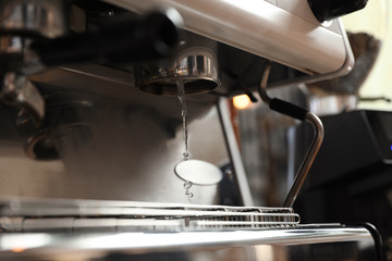 Water pouring from modern coffee machine, closeup