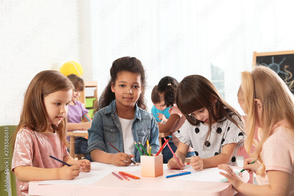 Wall mural Adorable children drawing together at table indoors. Kindergarten playtime activities