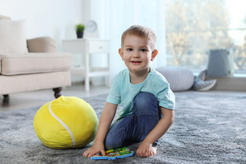 Fototapeta premium Cute child playing with soft toy on floor indoors