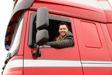 Portrait of happy driver in cab of modern truck