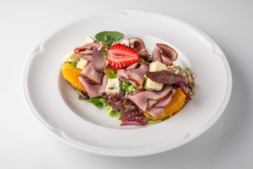 Salad of ham, prosciutto, pork or beef with vegetables, greens, berries and sauce. Nutritious, healthy dish. Banquet festive dishes. Gourmet restaurant menu. White background.