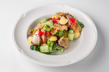 Delicious salad of smoked eel, fresh vegetables, quail eggs and crispy chips. Nutritious healthy dish. Banquet festive dishes. Gourmet restaurant menu. White background.