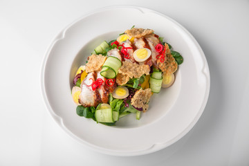 Delicious salad of smoked eel, fresh vegetables, quail eggs and crispy chips. Nutritious healthy dish. Banquet festive dishes. Gourmet restaurant menu. White background.