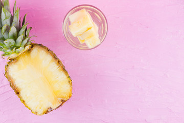 Pineapple and infused water on a pink background. Half of pineapple on a pastel background. Cocktail with pineapple and ice. Minimalism. Copy space