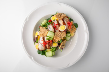 Delicious salad of smoked eel, fresh vegetables, quail eggs and crispy chips. Nutritious healthy dish. Banquet festive dishes. Gourmet restaurant menu. White background.