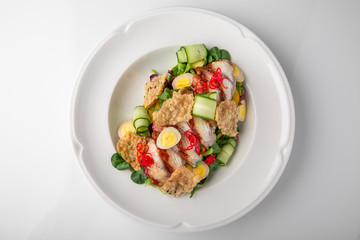 Delicious salad of smoked eel, fresh vegetables, quail eggs and crispy chips. Nutritious healthy dish. Banquet festive dishes. Gourmet restaurant menu. White background.