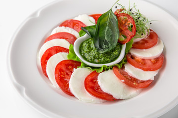Traditional caprese of tomatoes, mozzarella and pesto sauce. Nutritious healthy dish. Banquet festive dishes. Gourmet restaurant menu. White background.