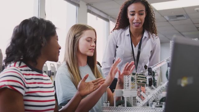 Teacher With Two Female College Students Building Machine In Science Robotics Or Engineering Class