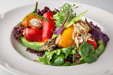 Salad of grilled vegetables in combination with fresh vegetables, cheese and sprouts of micro greens. Nutritious healthy dish. Banquet festive dishes. Gourmet restaurant menu. White background.