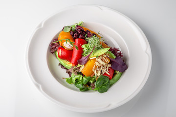 Salad of grilled vegetables in combination with fresh vegetables, cheese and sprouts of micro greens. Nutritious healthy dish. Banquet festive dishes. Gourmet restaurant menu. White background.