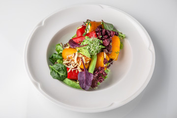 Salad of grilled vegetables in combination with fresh vegetables, cheese and sprouts of micro greens. Nutritious healthy dish. Banquet festive dishes. Gourmet restaurant menu. White background.