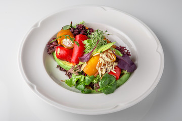 Salad of grilled vegetables in combination with fresh vegetables, cheese and sprouts of micro greens. Nutritious healthy dish. Banquet festive dishes. Gourmet restaurant menu. White background.