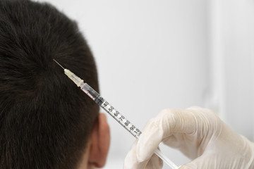 Man with hair loss problem receiving injection in salon, closeup