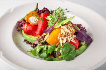 Salad of grilled vegetables in combination with fresh vegetables, cheese and sprouts of micro greens. Nutritious healthy dish. Banquet festive dishes. Gourmet restaurant menu. White background.