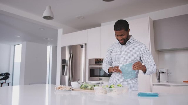 Man In Kitchen Preparing High Protein Meal And Putting Portions Into Plastic Containers