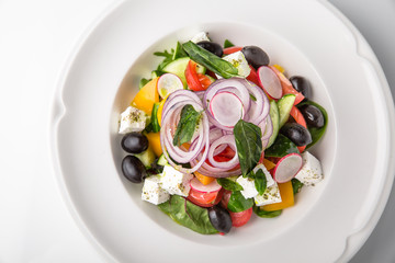 Traditional Greek salad with fresh vegetables, olives and cheese. Nutritious healthy dish. Banquet festive dishes. Gourmet restaurant menu. White background.