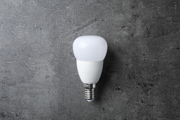 New modern lamp bulb on grey stone surface, top view
