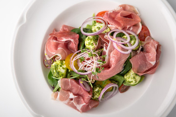 Salad of ham, prosciutto, pork or beef with vegetables, greens, berries and sauce. Nutritious, healthy dish. Banquet festive dishes. Gourmet restaurant menu. White background.