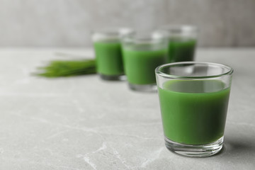 Glass of wheat grass juice on marble table. Space for text