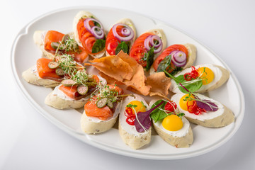 Bruschetta with salmon, avocado, capers, cucumber, radish, sweet pepper and cherry tomatoes. Banquet festive dishes. Fine dining restaurant menu. White background.