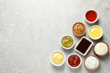 Fototapeta na wymiar Set of different delicious sauces on grey table, top view. Space for text