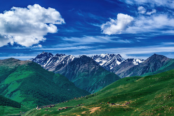 Beautiful view of alpine meadows in the Caucasus mountains. Pastures, meadows on the slopes and snow-capped mountains.