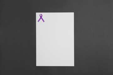 Purple awareness ribbon and blank card on black background, top view with space for text