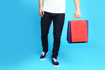 Naklejka premium Young man with paper bags on blue background, closeup